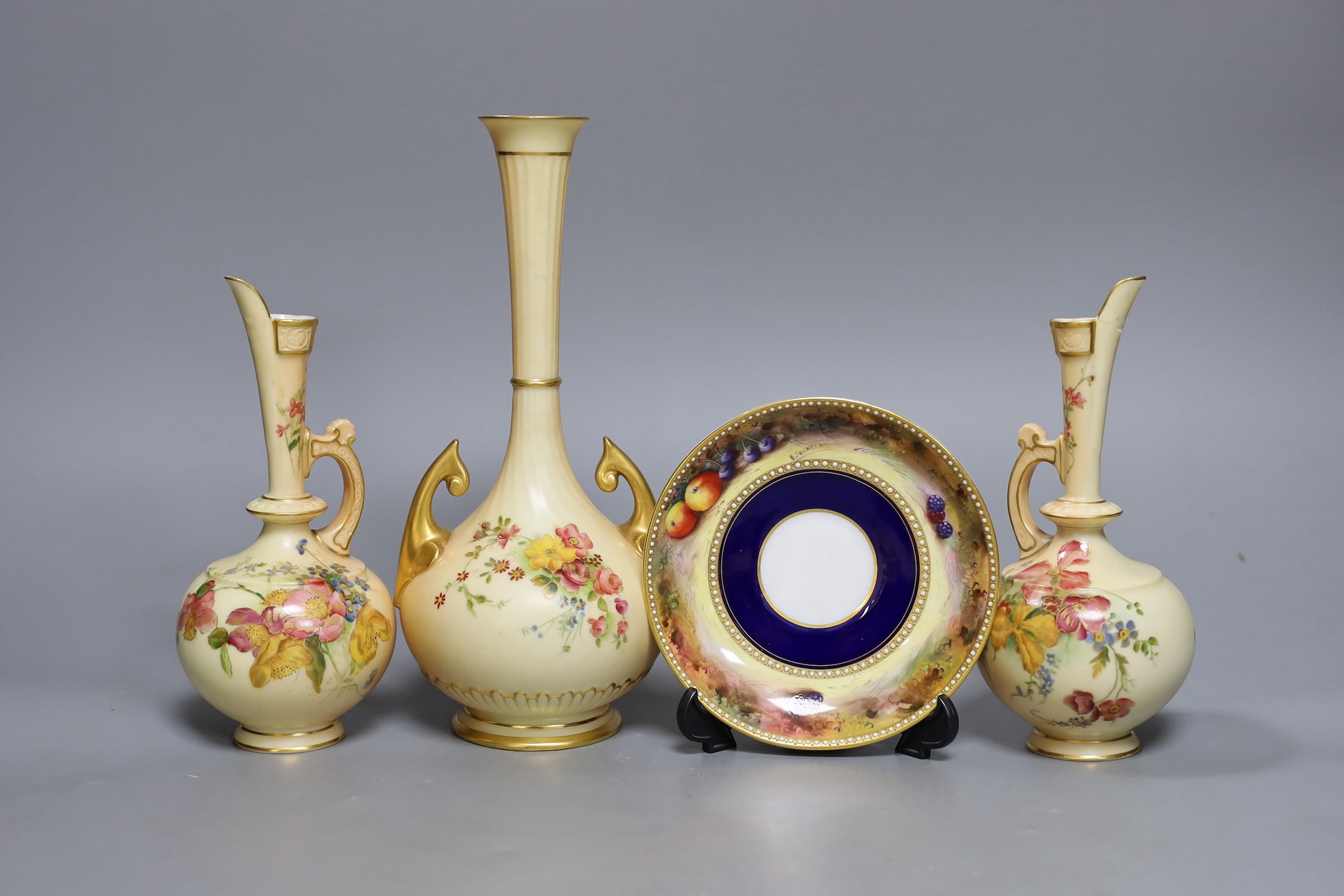 A pair of Royal Worcester blush ivory ewers, a similar vase and a beaded saucer decorated by E. Townsend, saucer 13.5cms diameter